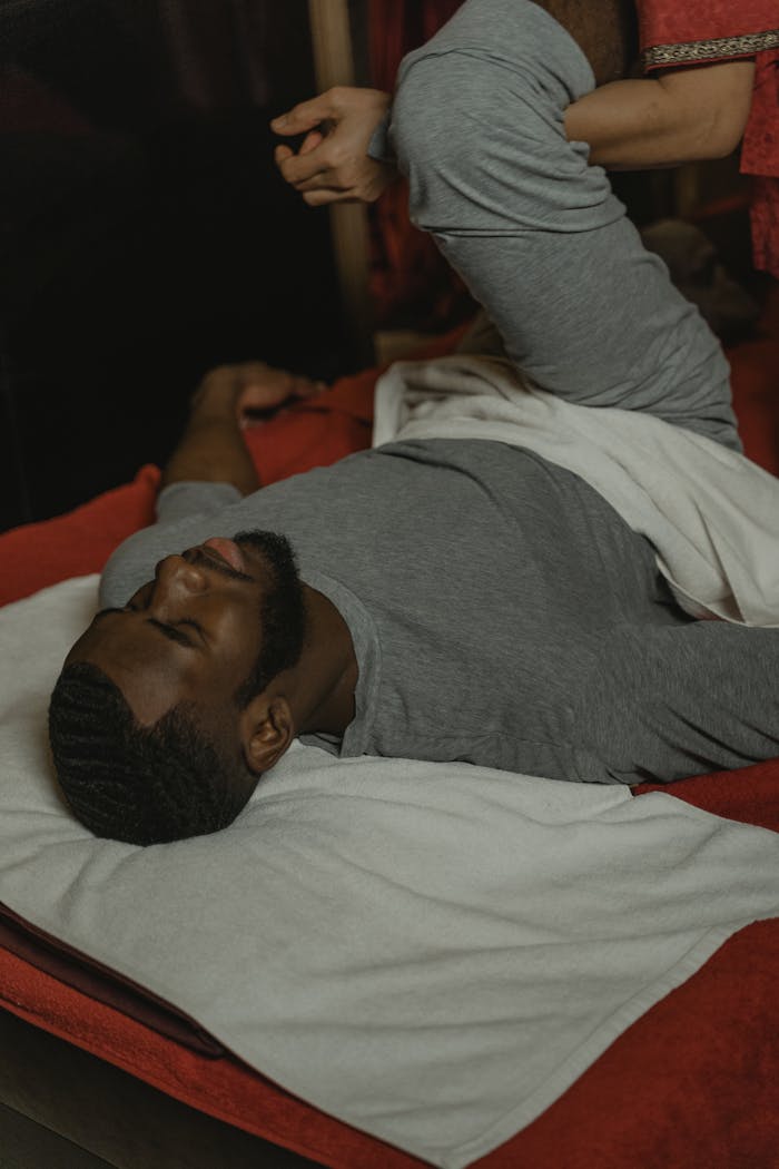 programs-04 An African American man relaxes while receiving a leg massage on a comfortable bed.